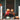 Two children in Halloween costumes sit on a porch, holding jack-o-lanterns in front of their faces. Pumpkins and Halloween decorations surround them.