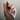 A hand gently holding a coiled measuring tape, with numbers visible, against a neutral background.