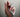 A hand gently holding a coiled measuring tape, with numbers visible, against a neutral background.