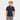 A smiling blond boy wears a Cat & Jack Boys' Short Sleeve Performance Uniform Polo Shirt in navy blue, made from recycled polyester, and gray pants. He stands with one hand in his pocket against a plain white background.