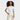 Smiling girl with curly hair wearing a Cat & Jack Girls’ Jersey Short Sleeve Polo T-Shirt in white and beige pants stands with one hand in her pocket against a plain white background.