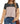 A woman wearing the LOLILRSD Women’s Color Block Long Sleeve Crewneck Tunic Top—featuring a relaxed fit with black, beige, and tan panels—paired with blue jeans, rings, a necklace, and a brown shoulder bag.