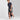 Wearing a navy striped tee, Men's Knit Shorts 6" - Original Use™ Dark Gray by Original Use, and white sneakers, a person walks with a dark backpack against a plain light-colored background.