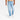 The lower half of a person in light wash Men's Relaxed Fit Jeans by Goodfellow & Co, paired with a beige shirt and white sneakers, is shown against a plain white background. The jeans feature midweight stretch denim and a mid-rise fit.