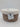 A small, round natural woven wicker storage basket from Bullseye’s Playground™ featuring a fitted white lid and a front label that reads “Natural Woven Wicker Storage Basket – Small w/ White Lid.” The background is plain white.
