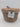 A small, round Natural Woven Wicker Storage Basket with a wicker lid from Bullseye’s Playground™ is shown against a plain white background. The basket features a white label on the front that reads “Natural Basket with Lid.”.
