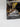 A gray Jurassic World Camouflage N Battle Indominus Rex Action Figure Toy by Mattel, featuring sharp teeth, claws, and a ridged back, stands on two legs in a dynamic walking pose against a white background. This action figure boasts lights, sound, and motion—perfect for Jurassic World fans and ready for Augmented Reality adventures.