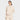 A woman in the JoyLab Women's French Terry 1/2 Zip Hooded Pullover Sweatshirt in Cream stands against a white background, one hand in her front pocket and a slight smile on her face.