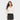 A woman with long brown hair wears a Women's Long Sleeve Smocked Blouse - Universal Thread™ Cream, made from lightweight fabric, and a black studded denim skirt, standing against a plain light background.