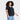 A person with curly hair is wearing the Ava & Viv Women’s Short Sleeve V-Neck T-Shirt in black, a midweight pullover style that falls below the waist, paired with light blue jeans, standing against a plain white background and smiling slightly.