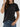 A person wearing a black Women’s Wrinkle-Free Short Sleeve Crew Neck T-Shirt tucked into blue jeans.