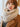 A person wearing a Wander Agio Women’s Warm Winter Infinity Blanket Scarf in beige, draped around their neck over a brown coat.