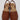 The Kenneth Cole Reaction Women’s Fine Glass Wedge Sandal is a stylish women’s brown open-toe wedge sandal featuring a closed front, open heel, and slingback strap. It showcases matching brown material on the sole and heel with visible stitching along the upper edge.