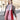 A person wears a Women’s Oversized Plaid Winter Blanket Scarf Pink, Black & Red in an oversized, fringed red, pink, and white plaid pattern over a textured corduroy quarter-zip pullover.
